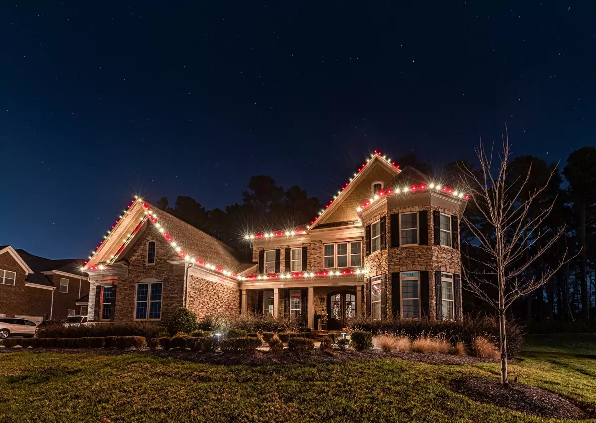 Brick and stone home with every roofline in alternating red and warm white C9 bulbs